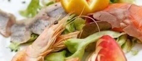 A plate of seafood salad with shrimp, lettuce, and a lemon slice.