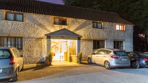 A stone building with a sign reading "Auberge du Colombier." There are parked cars in front, and the entrance is illuminated. - Auberge du Colombier (Guines)