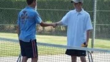 Deux personnes se serrent la main sur un court de tennis.