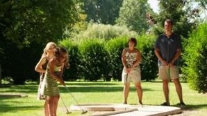 A person playing croquet on a grass field with a wooden hoop. - Auberge du Colombier (Guines)