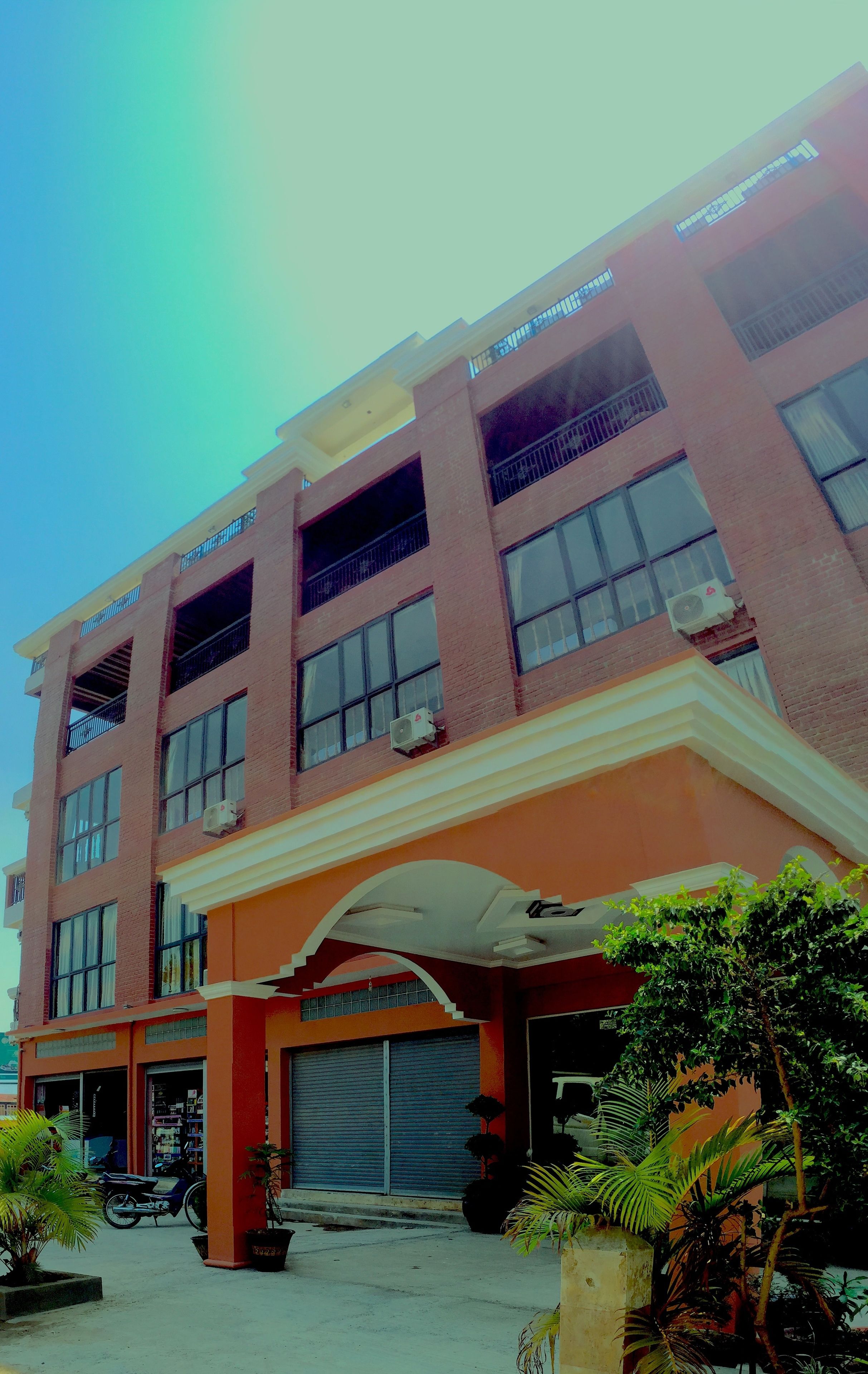A multi-story building with a flat roof, large windows, and a covered entrance.