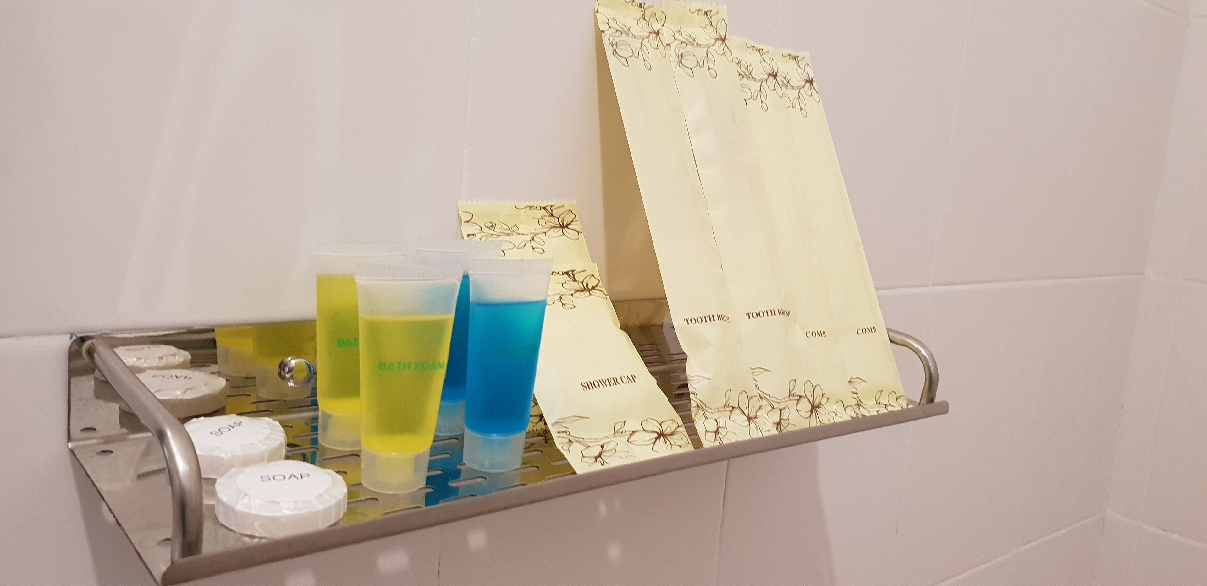 A bathroom shelf with toiletries including soap, shampoo, conditioner, and shower cap.