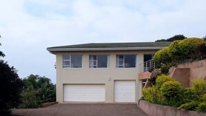 A two-story house with a paved driveway and a garage. - Shelbourne Sea (Port Shepstone)