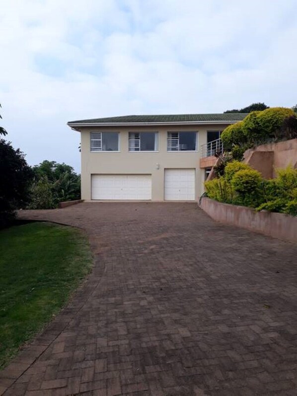 A two-story house with a paved driveway and a garage. - Shelbourne Sea (Port Shepstone)