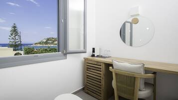 A modern bathroom with a large window, a round mirror, a wooden vanity, and a chair.