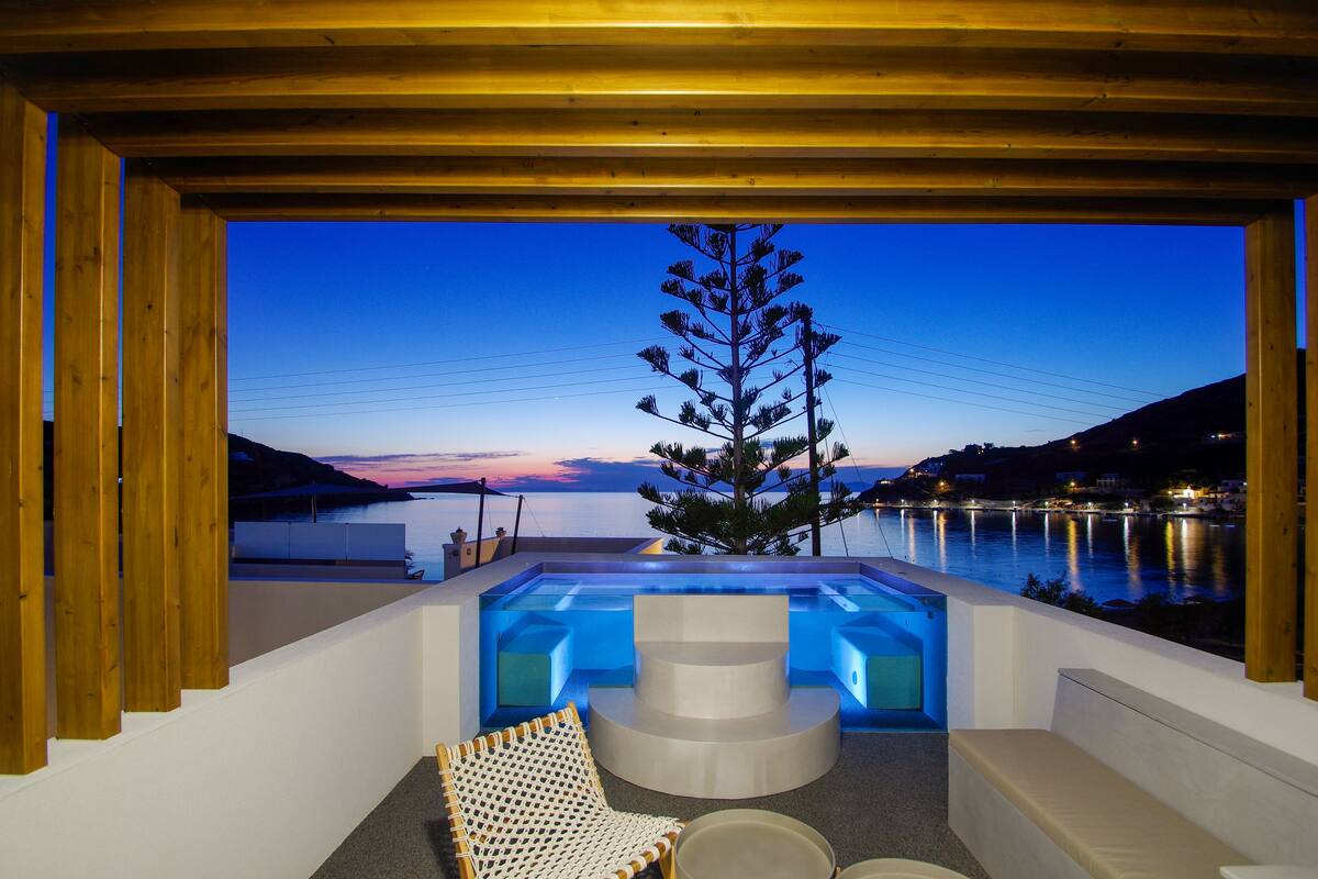 A modern outdoor hot tub area with a view of a lake and mountains at dusk.