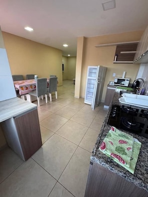 Une cuisine équipée d’un four à micro-ondes, d’une cuisinière et de placards. On y trouve également un coin repas avec des chaises et une table.