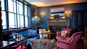A cozy room with a blue sofa, floral armchairs, a wooden table, and a fireplace. - The Old Vicarage (Bridgwater)