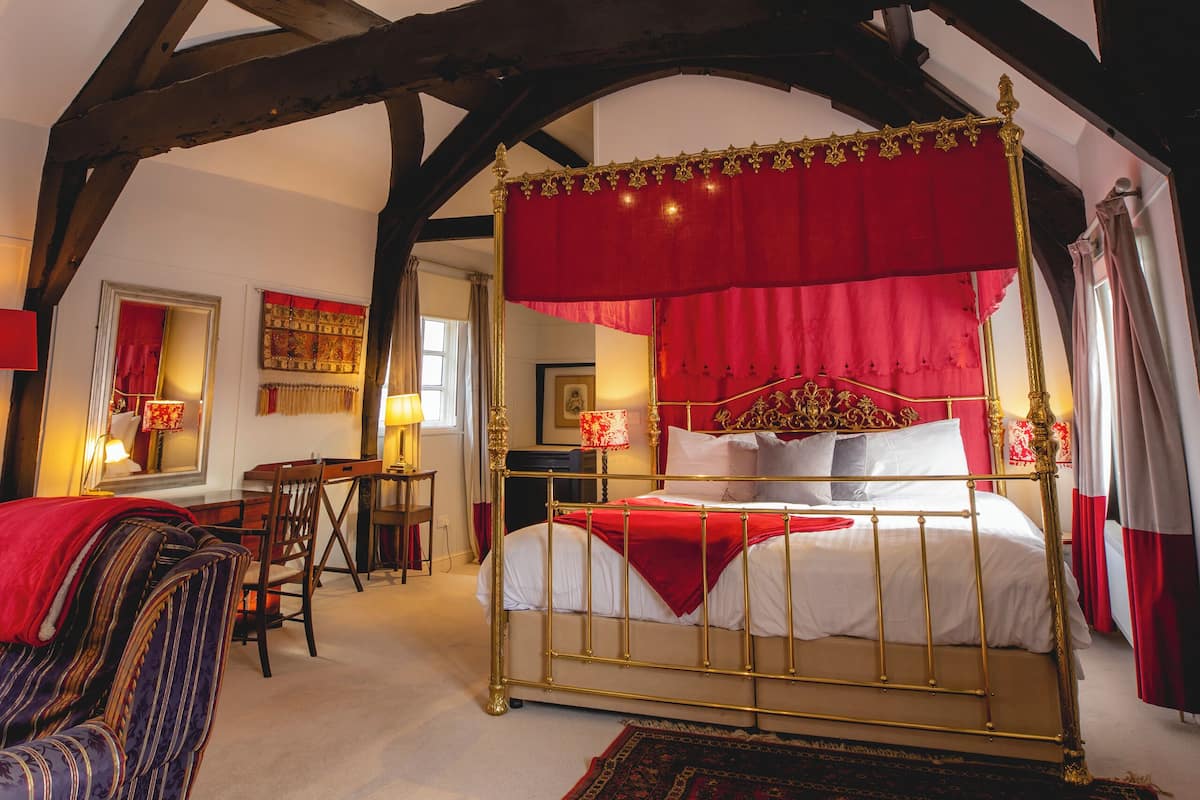 Une chambre à coucher avec un lit à baldaquin, un dais rouge, un plafond en bois et une moquette à motifs.