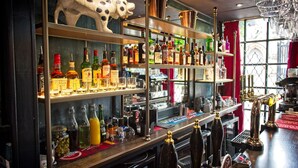 A bar with shelves of liquor bottles, a beer tap, and a Dalmatian sculpture. - The Old Vicarage (Bridgwater)