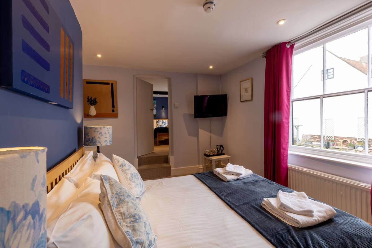 Une chambre d’hôtel avec un lit, une télévision, une fenêtre avec des rideaux et une vue sur l’extérieur.