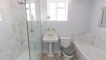 A bathroom with a glass-enclosed shower, a pedestal sink, a toilet, and a bathtub.
