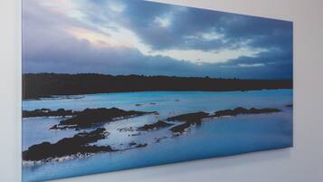 A landscape painting of a coastal scene with calm water and a cloudy sky.