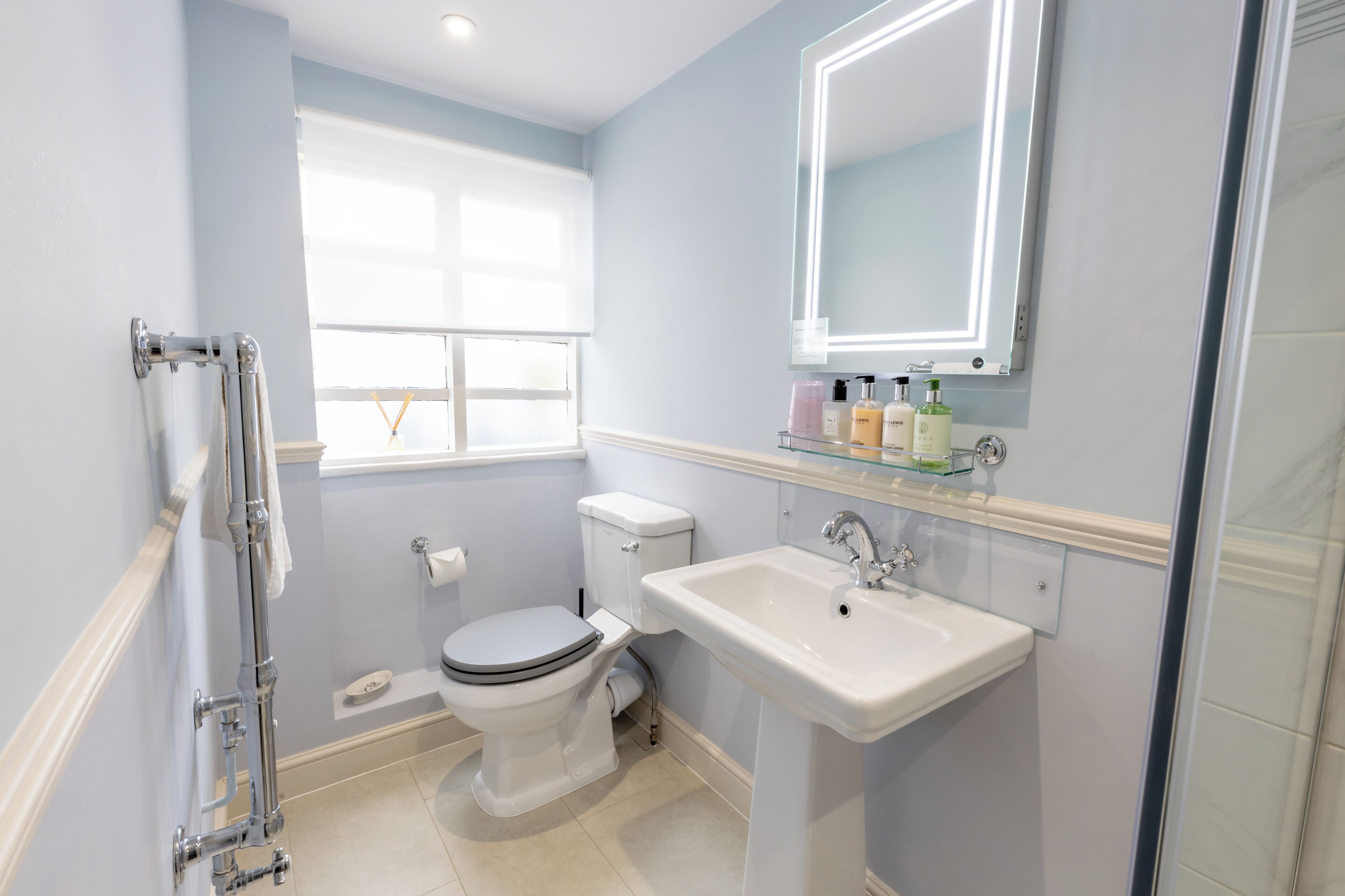 A bathroom with a toilet, sink, and window.