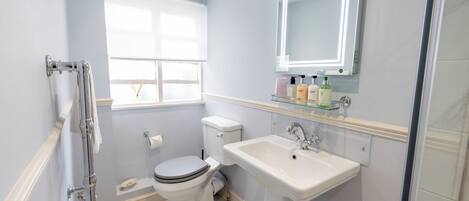 A bathroom with a toilet, sink, and window.
