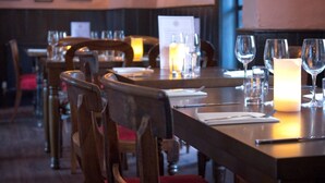 A restaurant interior with wooden tables, chairs, and a candle on the table. - The Old Vicarage (Bridgwater)
