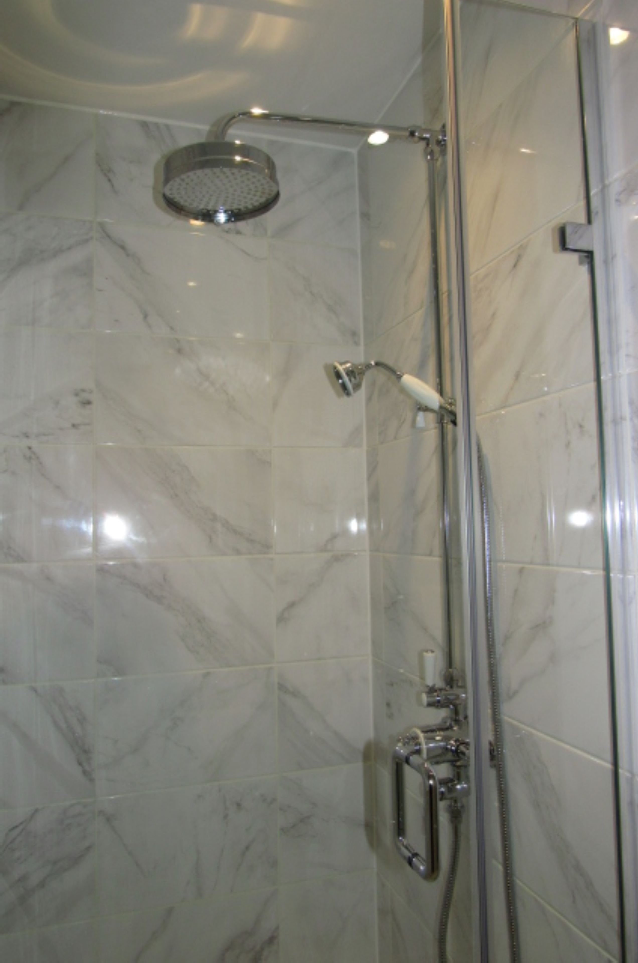 A shower with a handheld showerhead and a wall-mounted faucet.