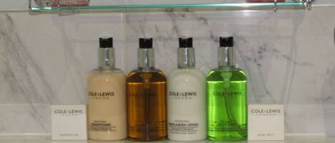 A bathroom shelf with four bottles of Cole + Lewis products.