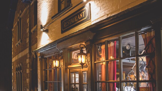 A restaurant with a brick facade, illuminated signage, and traditional window displays. - The Old Vicarage (Bridgwater)