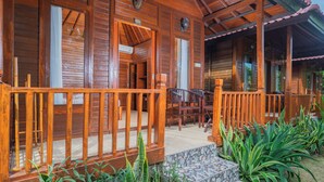 Una cabaña de madera con un porche, escalones de piedra y mobiliario exterior.