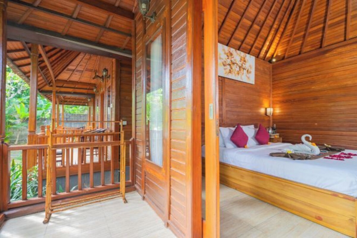 A wooden room with a bed, a nightstand, and a window.