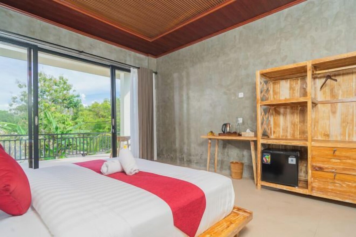 Un dormitorio con una cama grande, un banco de madera, una mesita pequeña y vistas a zonas verdes.