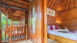 Una habitación de madera con cama, balcón y vista a la vegetación.