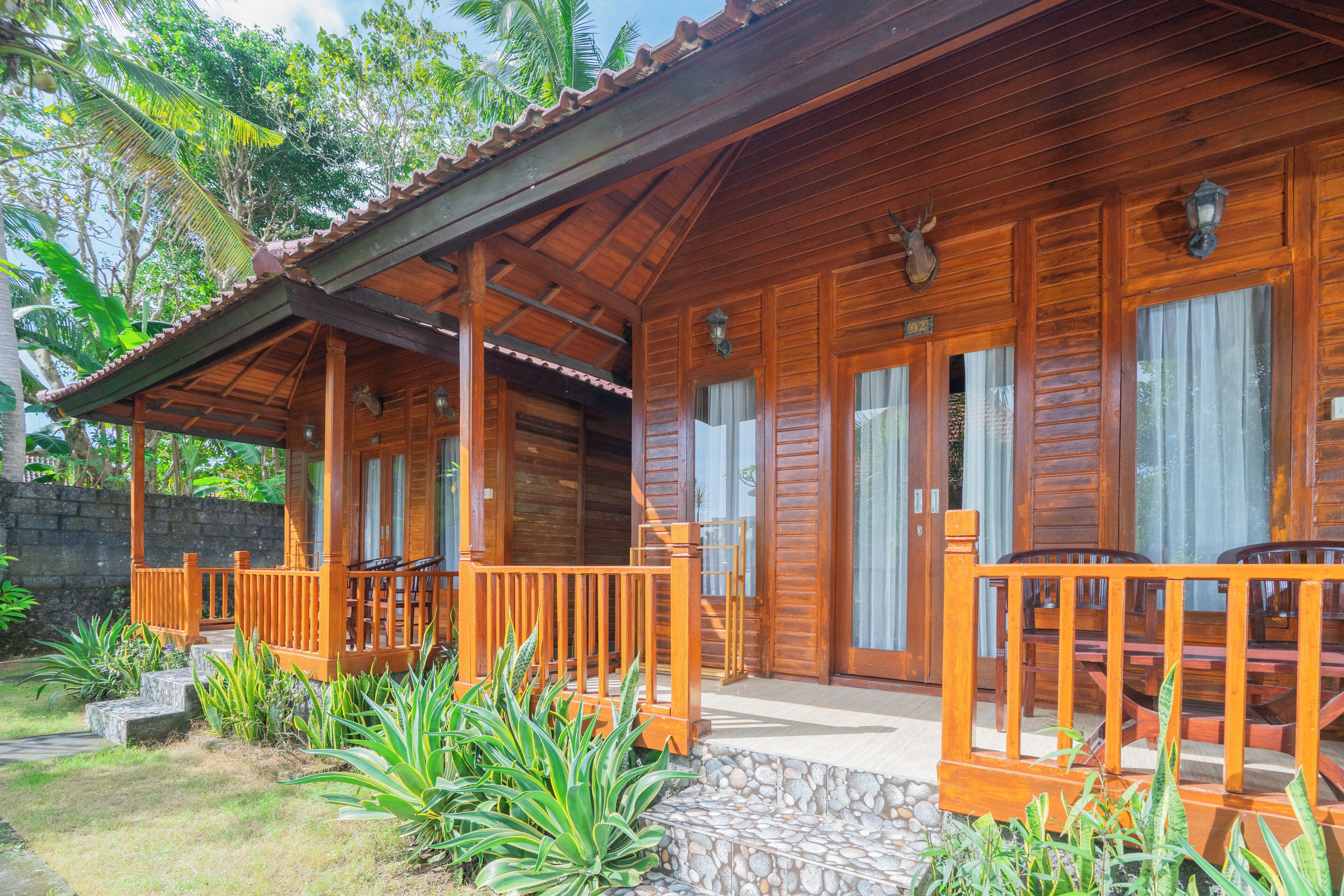 A wooden cabin with a porch, stone steps, and a view of the surrounding greenery.