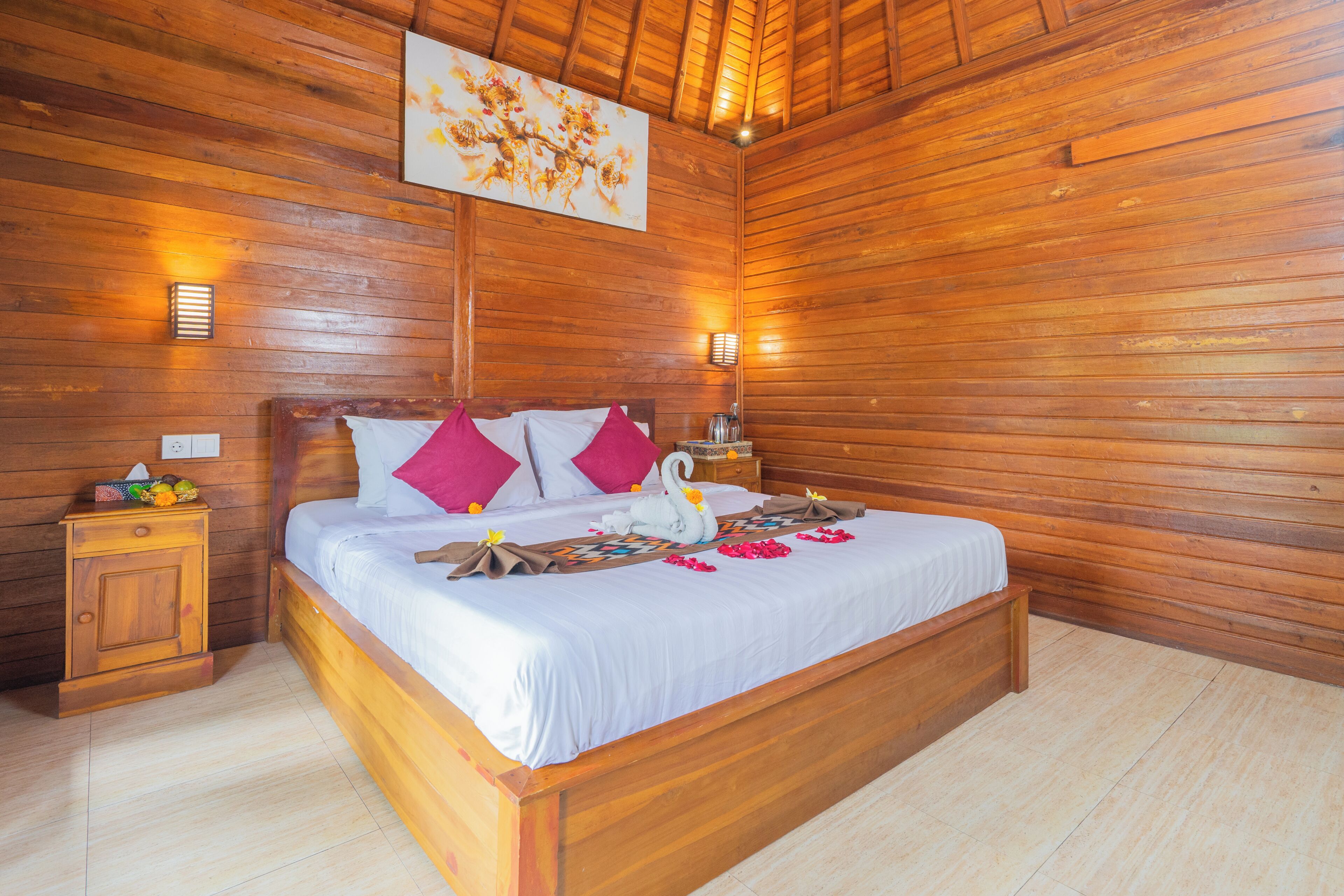A wooden-paneled room with a bed, two bedside tables, and a wall-mounted light fixture.