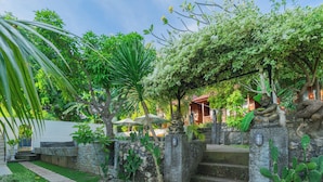 Un jardín con una escalera de piedra, un edificio blanco y un árbol con flores blancas.