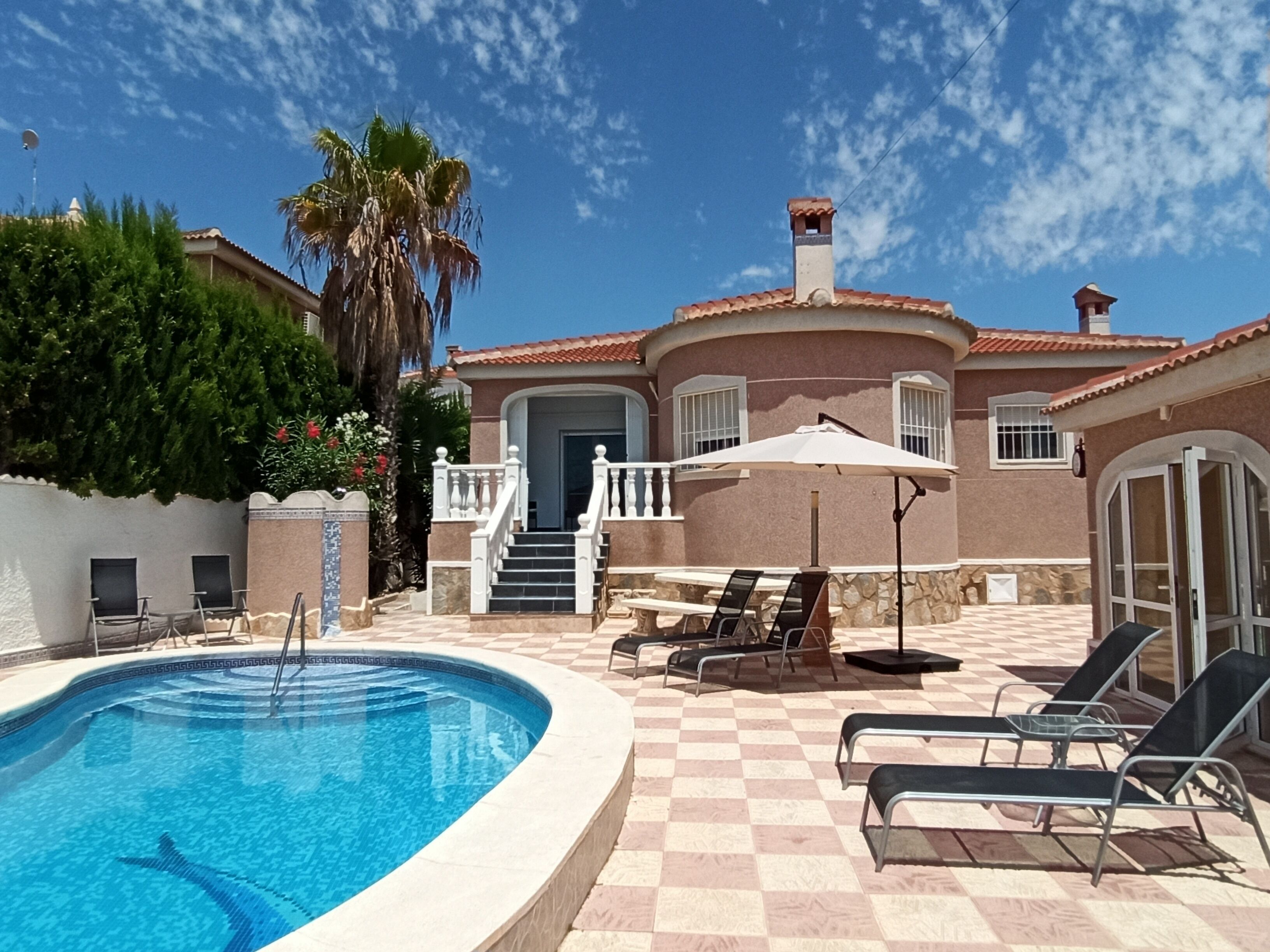 A pool area with a checkered floor, lounge chairs, and a staircase leading to a door.