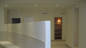 Un pasillo con un separador blanco, una puerta que da a una habitación y un suelo de baldosas.