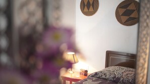 Un dormitorio con cama, mesita de noche, lámpara y adornos en la pared.