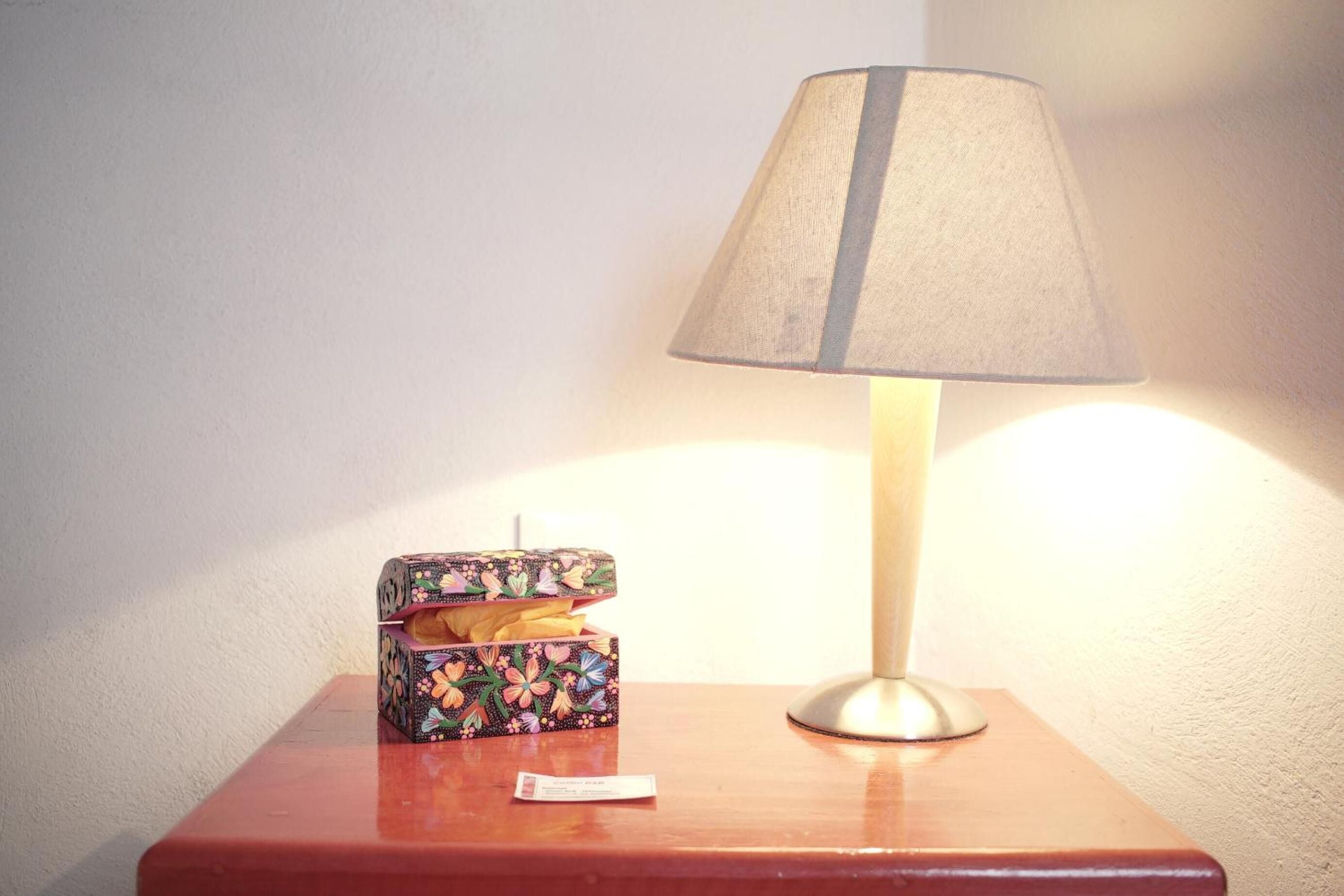 Una mesita de noche con una lámpara y una caja estampada con flores.