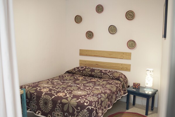 A bedroom with a bed, a nightstand, and wall decorations.