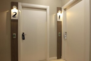 A hallway with two doors, each marked with a number and a light above. - Eibarrooms (Eibar)