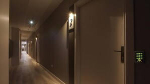 A hotel corridor with doors numbered, a hallway, and a door with a keypad lock.