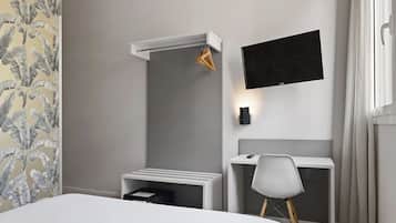 A hotel room with a bed, a desk, a chair, a TV, and a shower area.