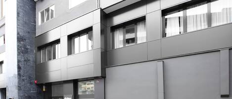 Un edificio moderno con varios pisos, ventanas amplias y un imponente pilar negro.