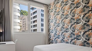 A bedroom with a bed, a desk, and a window with curtains. - Eibarrooms (Eibar)