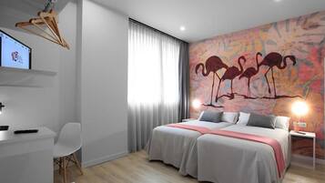 A modern hotel room with a bed, a desk, and a TV.