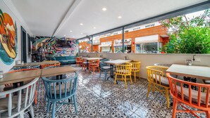 A restaurant with colorful chairs and tables, a patterned floor, and a mural on the wall. - İsinda Pansiyon (Kas)