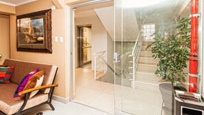 A modern living room with a sofa, a framed picture, and a staircase leading to an upper level.