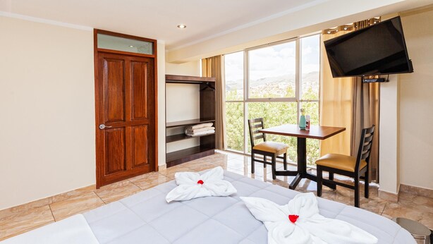 A hotel room with a bed, a desk, a TV, a window with a view, and a wardrobe.