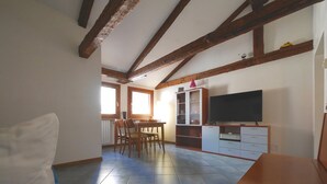 Un salon équipé d’un téléviseur, de meubles en bois et d’un coin repas avec des chaises et une table.