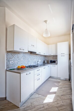 Uma cozinha moderna com armários brancos, painel de fundo estampado e piso de madeira.