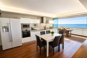 Una cocina moderna con comedor, vistas al mar y un balcón con mobiliario de exterior.