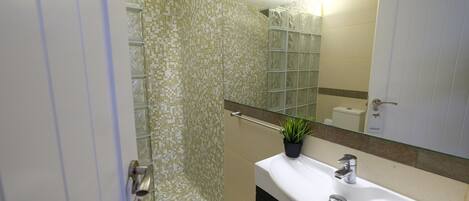 A bathroom with a glass shower enclosure, a white sink, and a mirror above it.