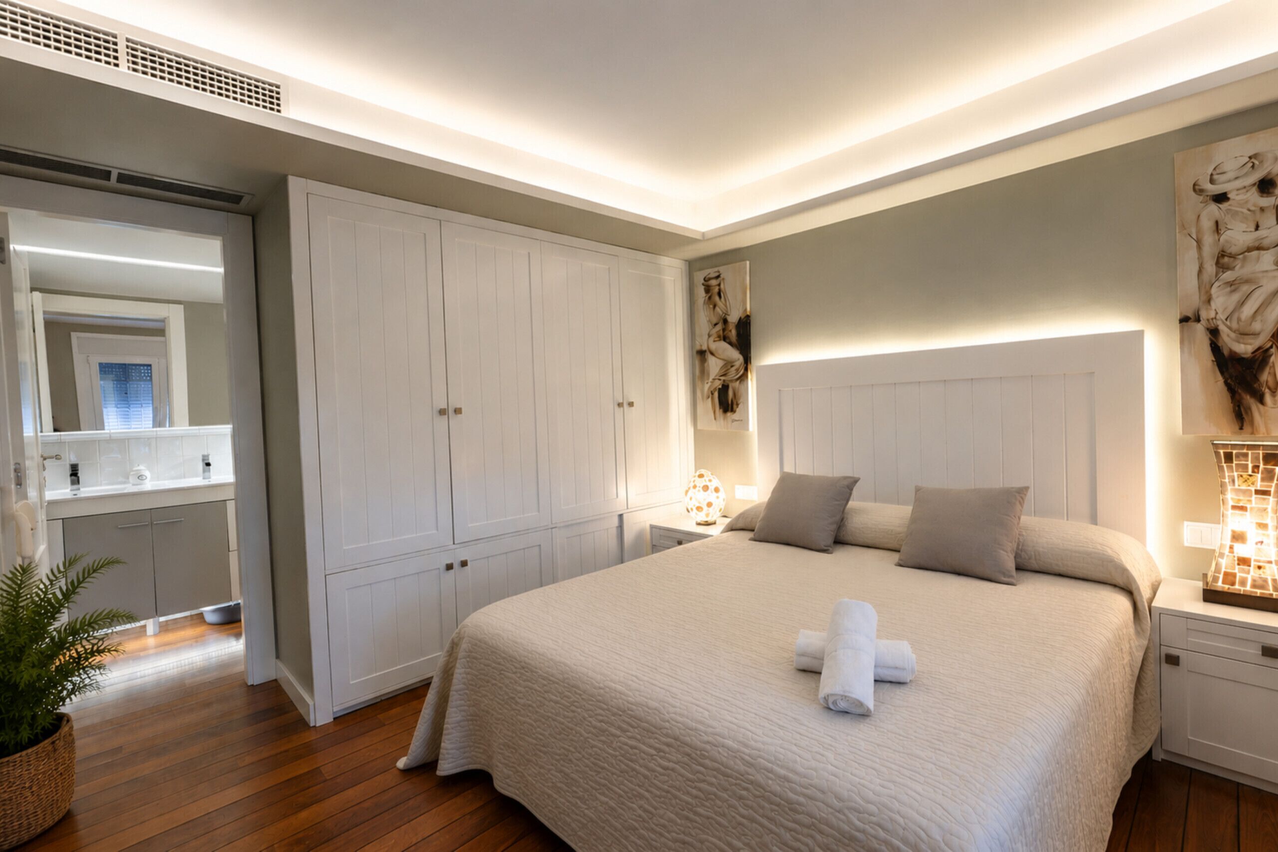 Ein Schlafzimmer mit einem großen Bett, einem Kleiderschrank, einem Nachttisch mit Lampe und einem Wandbild.