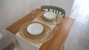 A dining table set with two plates, cutlery, and wine glasses, accompanied by a green chair. - Apricot House. In the heart of the old town. (Bari)